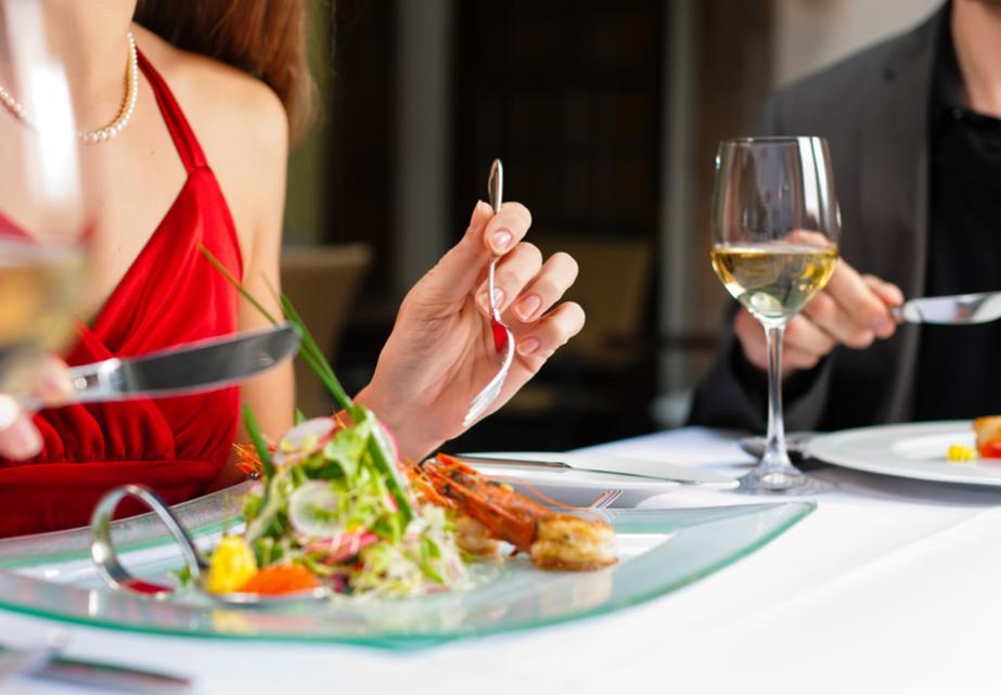 Cena elegante con piatti raffinati e calici di vino, atmosfera romantica.