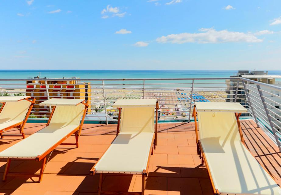 Sdraio su terrazza, vista mare e cielo azzurro, atmosfera rilassante e serena.