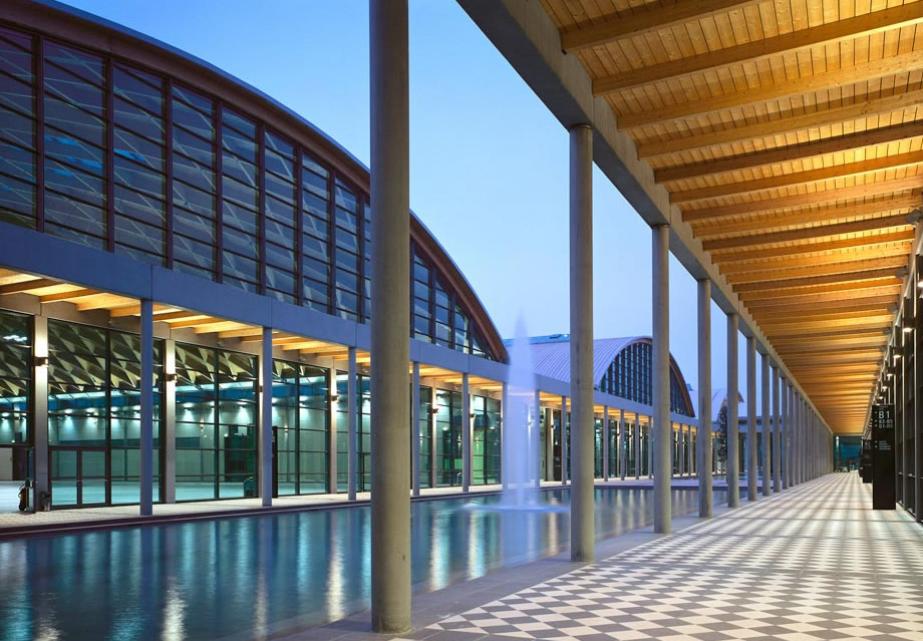 Architettura moderna con colonne, riflessi d'acqua e luce calda, creando un'atmosfera serena.